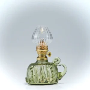 Petrolejová lampa ze zeleného lesního skla s ozdobným cylindrem.